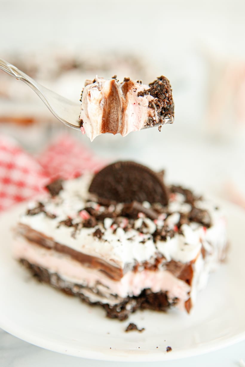Close-Up of Chocolate Peppermint Lush Bite on a Fork A fork holding a bite of dessert, showing creamy layers of chocolate, peppermint, and whipped topping with a sprinkle of crushed candy cane.