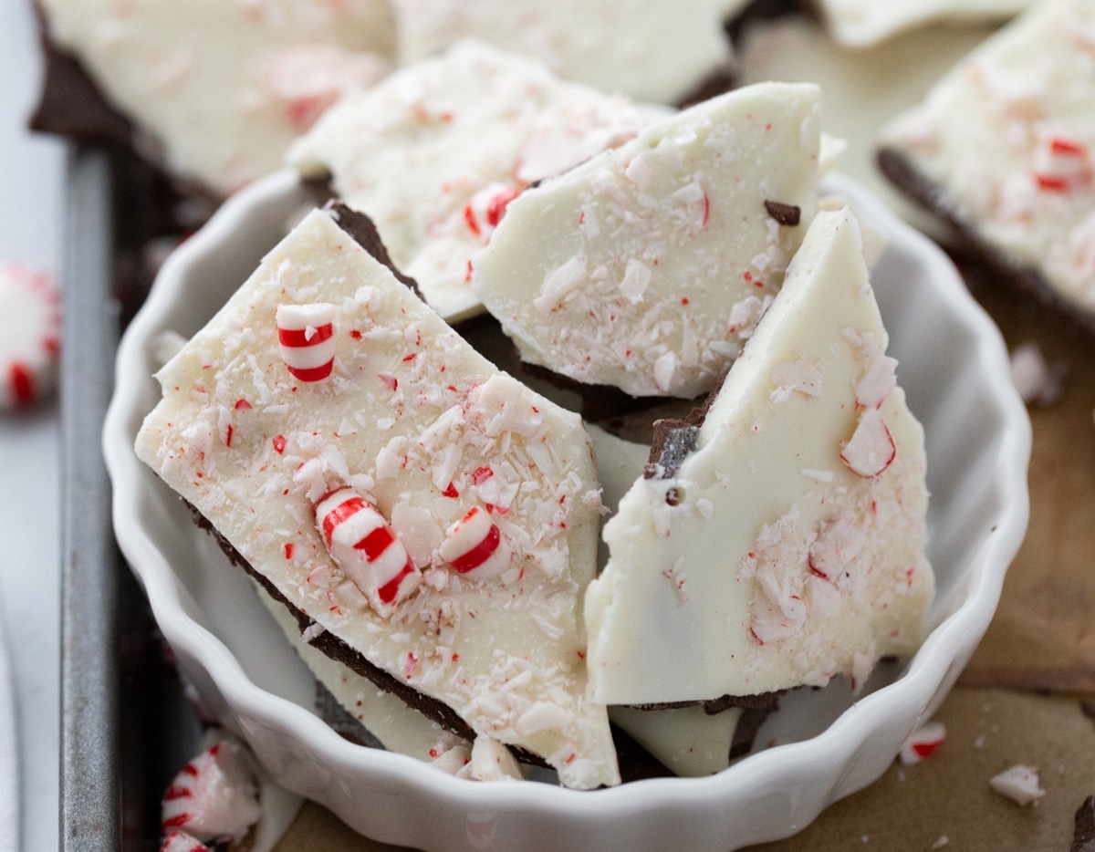 Double chocolate peppermint bark pieces in a white bowl, sitting on a baking tray.