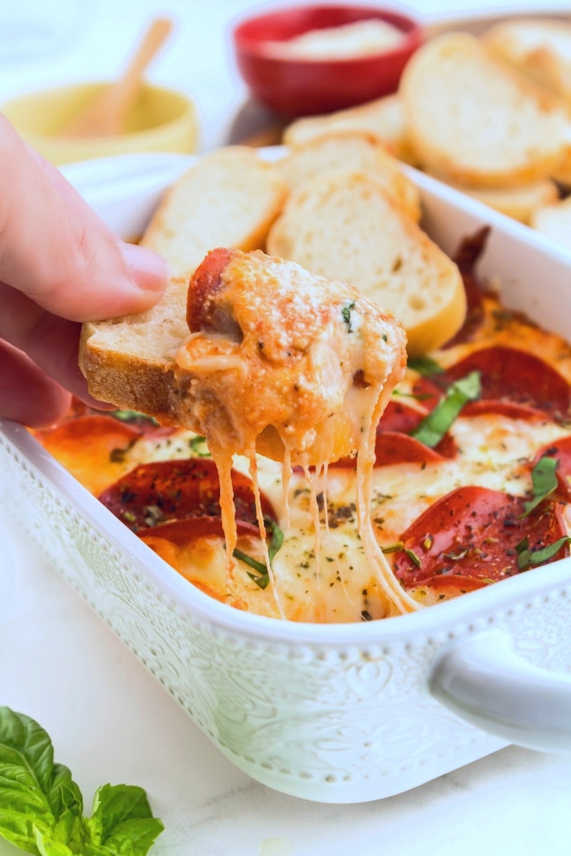 A scoop of Gooey Pizza Dip pizza dip being scooped out with bread