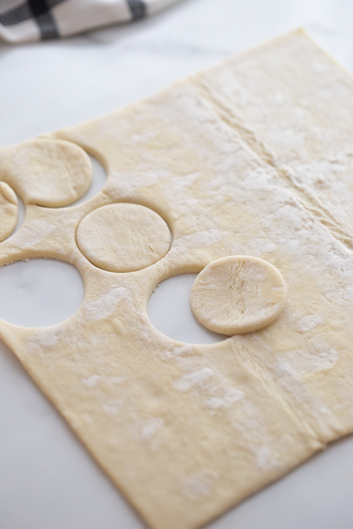 Puff pastry sheet with several rounds cut out using a cookie cutter.