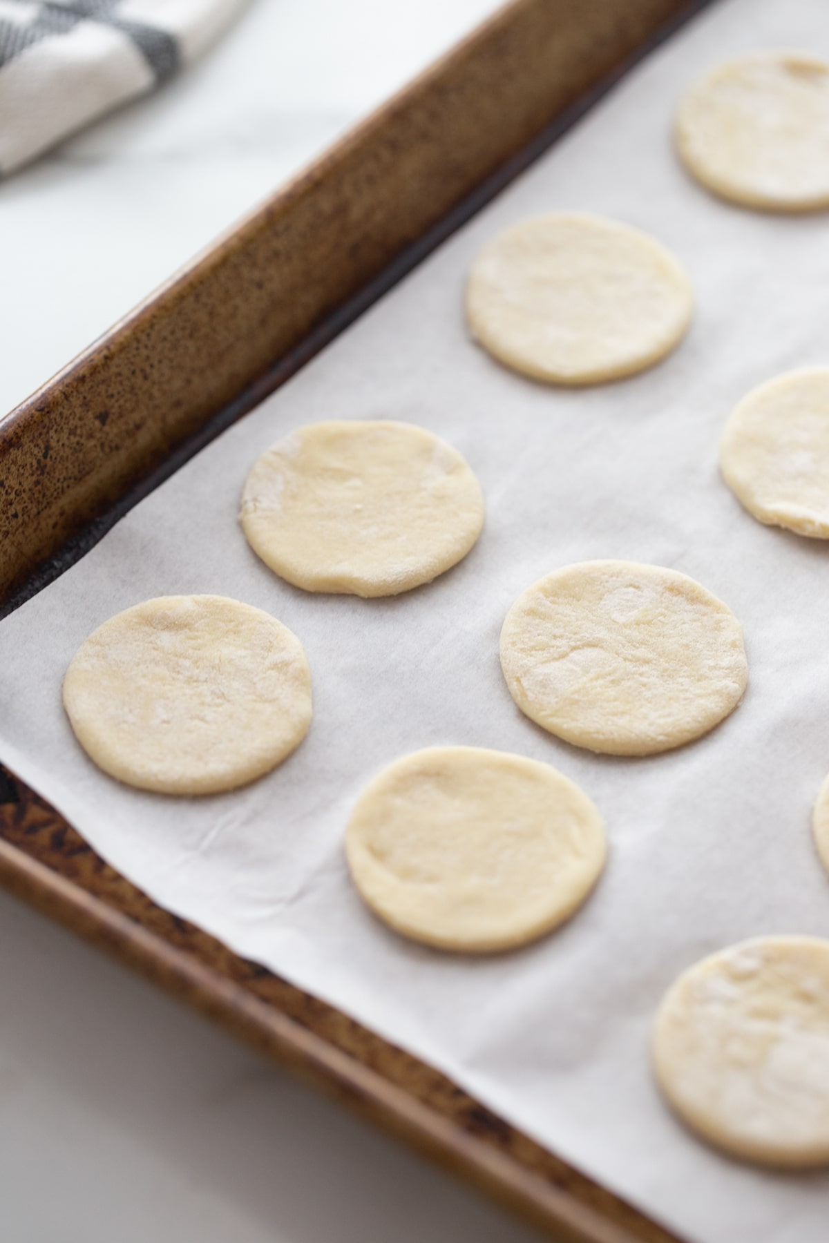 Puff pastry rounds arranged on a parchment-lined baking sheet, ready for filling.