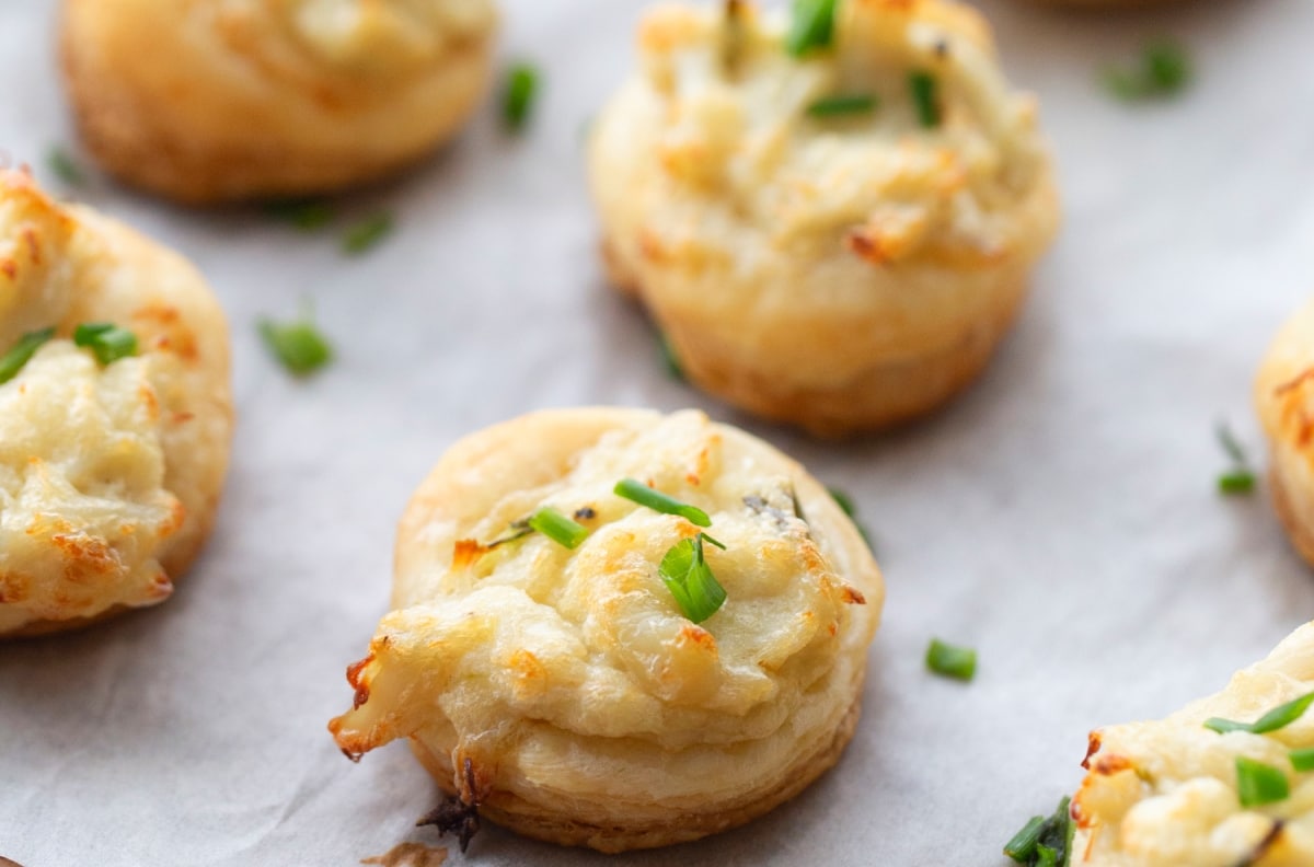 Close-up view of a flaky, golden crab and chive puff showing the creamy filling.