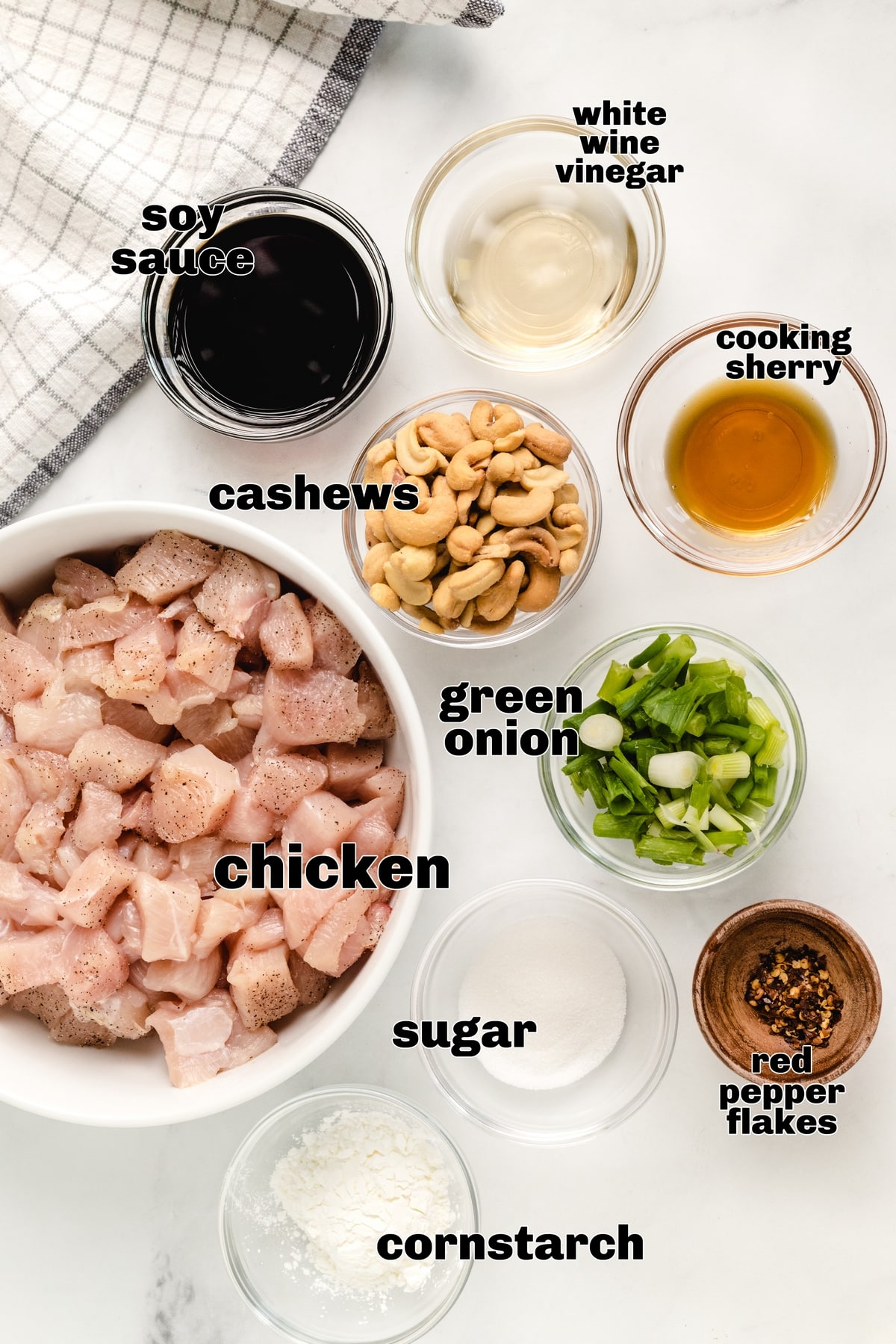 Kung Pao Chicken Ingredients - Chicken, Cashews, Soy Sauce, and More. Ingredients for kung pao chicken laid out, including chicken, soy sauce, cashews, red pepper flakes, and green onions.