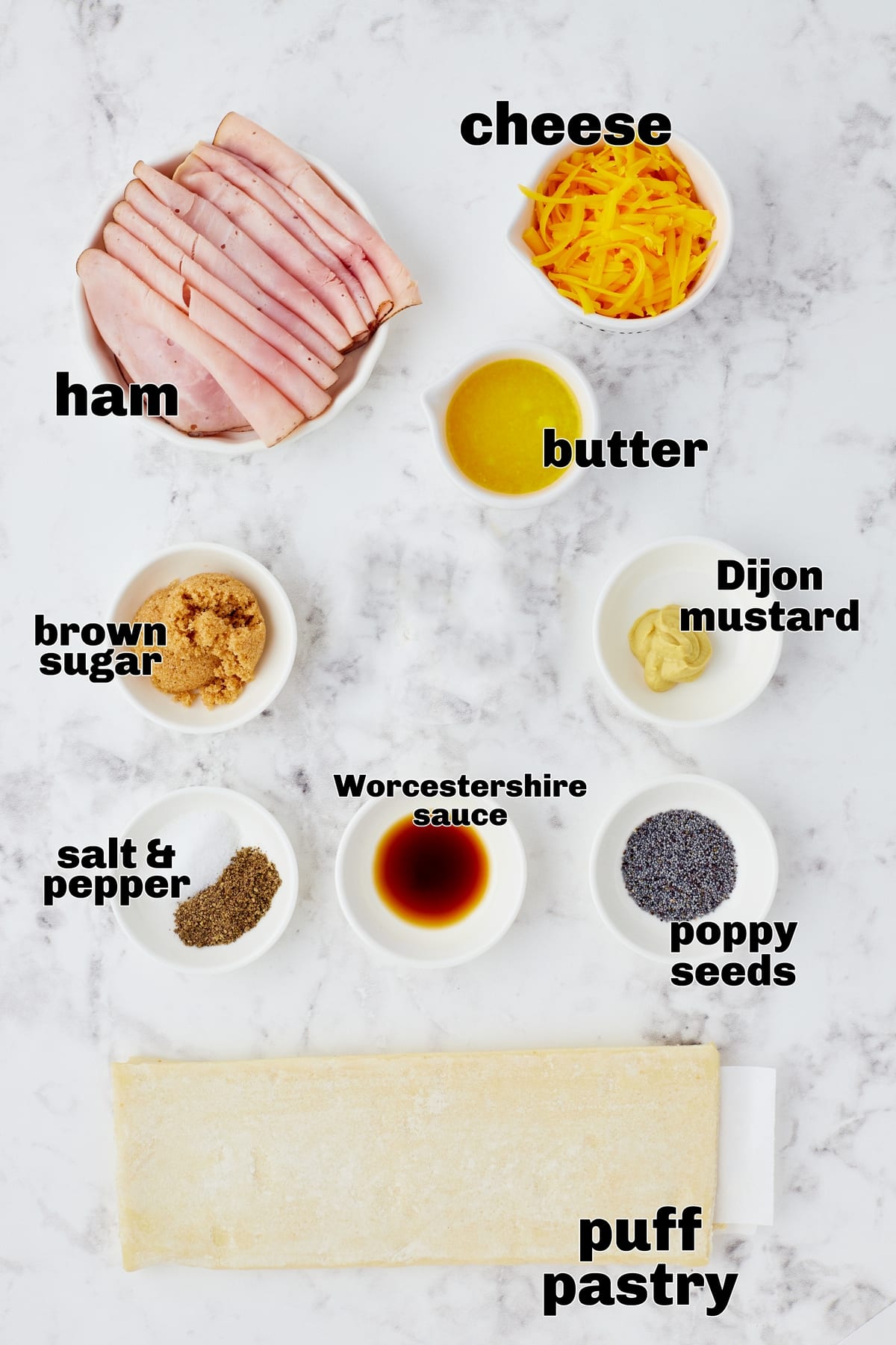 Ingredients laid out on a countertop: puff pastry, deli ham, shredded cheese, and seasoning.