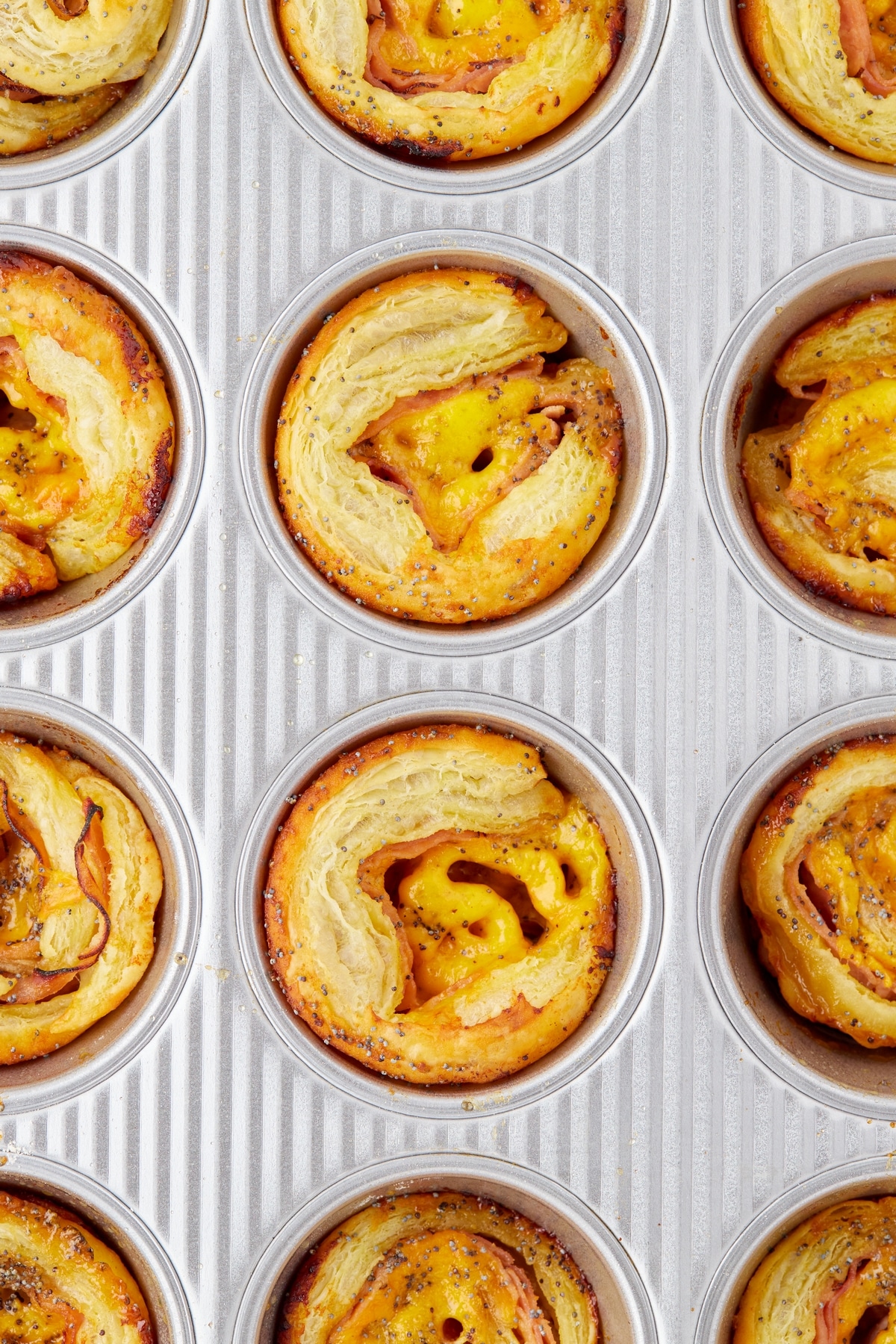 Ham and cheese pinwheels in a muffin tin, fresh out of the oven.