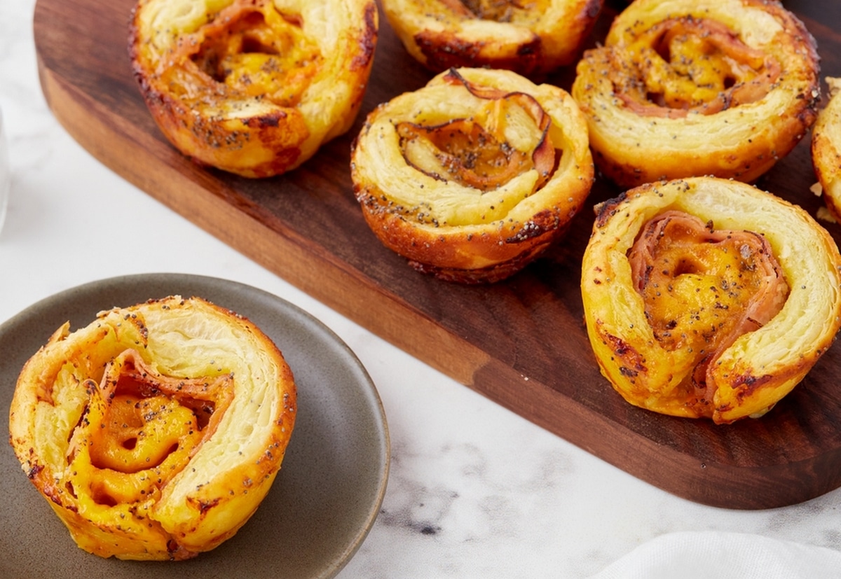 Flaky puff pastry rolls filled with ham and melted cheese, ready to serve.