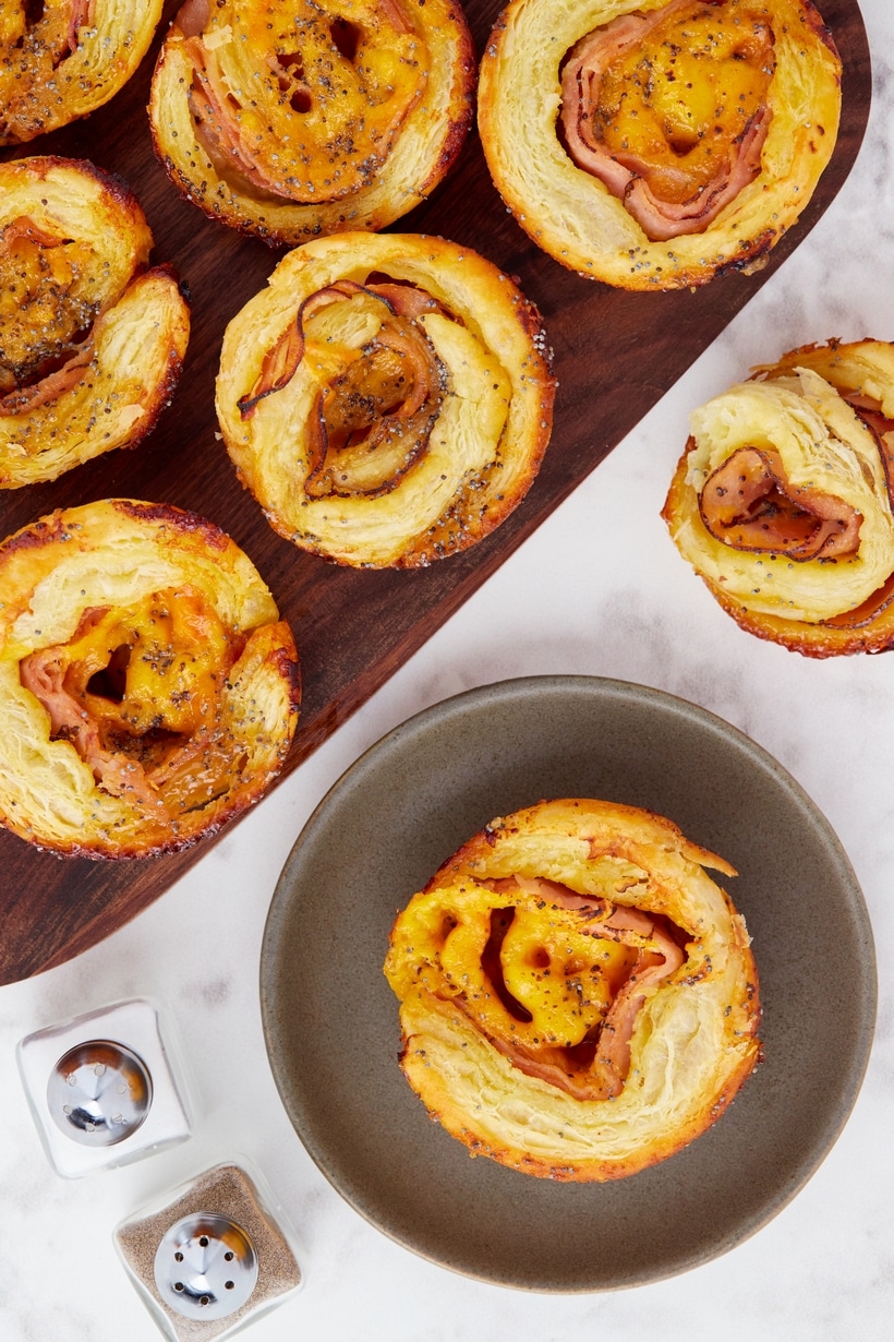 Close-up shot of golden brown ham and cheese pinwheels on a plate.