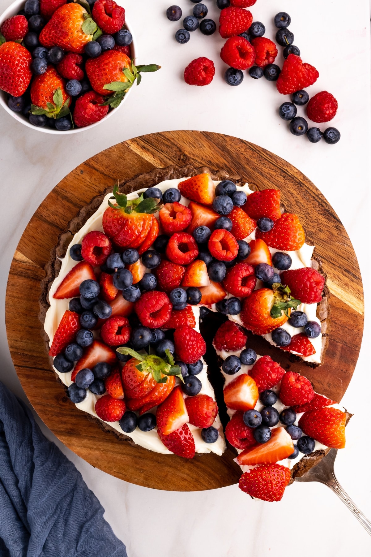 fruit-topped brownie pizza with cream cheese frosting Brownie pizza dessert topped with strawberries, blueberries, and raspberries