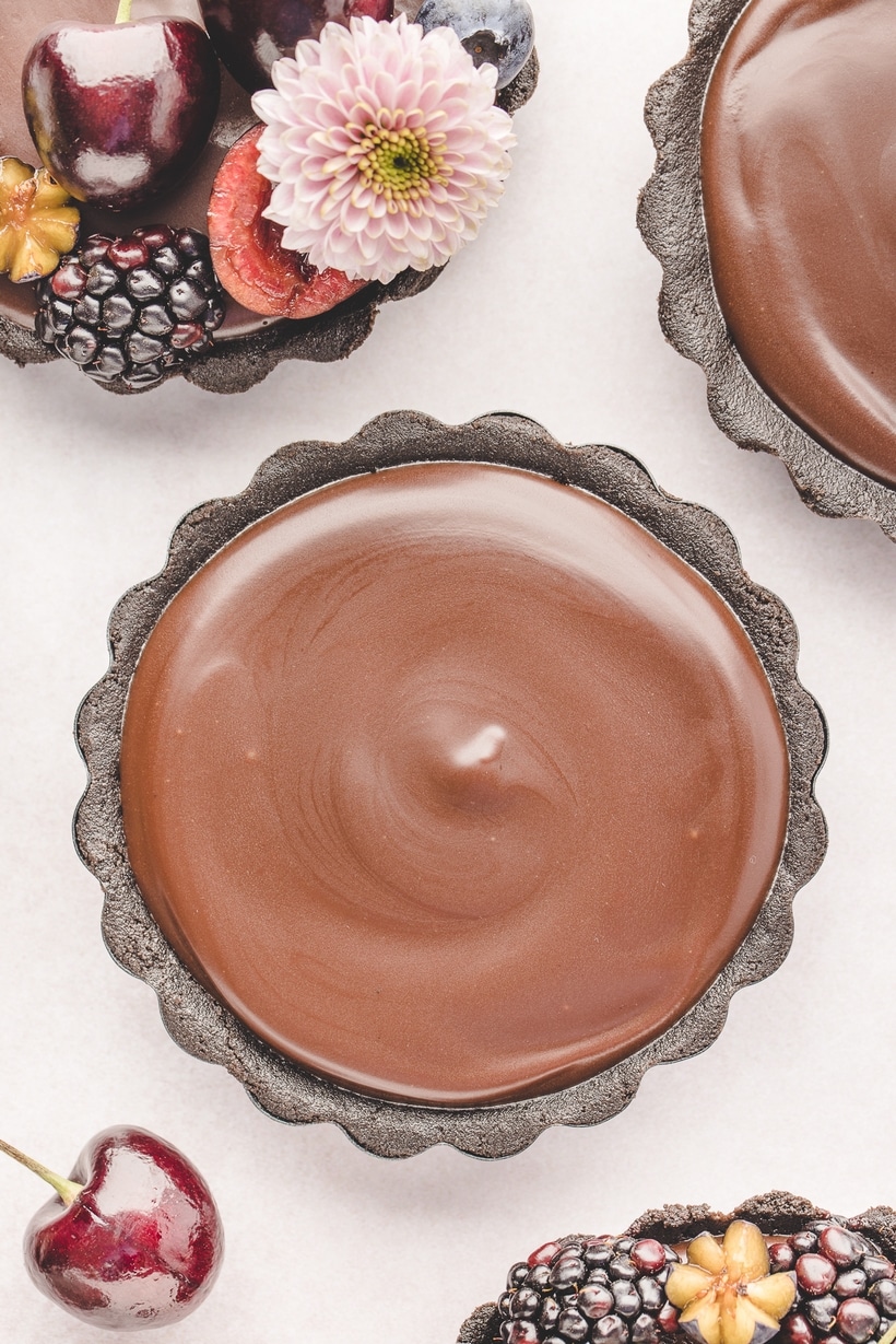 top view Mini Chocolate Ganache Tarts Overhead view of a plain mini chocolate ganache tart with a glossy, smooth ganache top and no toppings.