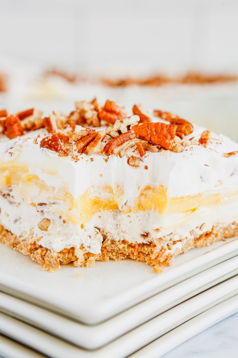 Pecan Cream Pie Lush Slice on White Plates A slice of Pecan Cream Pie Lush served on a stack of white plates, ready to enjoy.