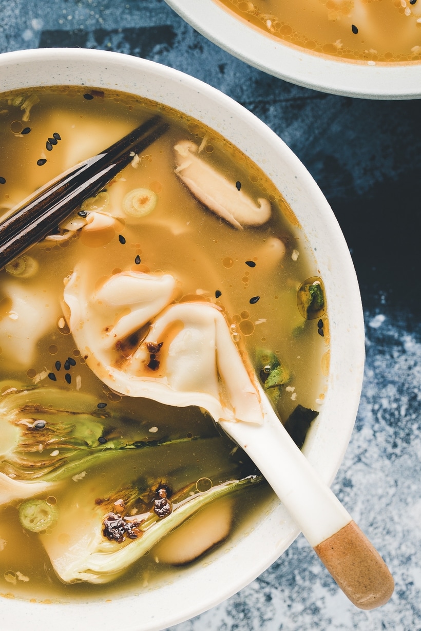 Homemade Wonton Soup with Bok Choy and Chili Oil A bowl of wonton soup with tender wontons, bok choy, and a flavorful broth, garnished with scallions, sesame seeds, and chili oil.