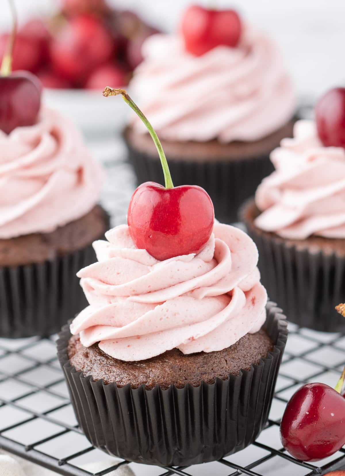 Freshly baked chocolate cherry cupcakes cooling on a wire rack 