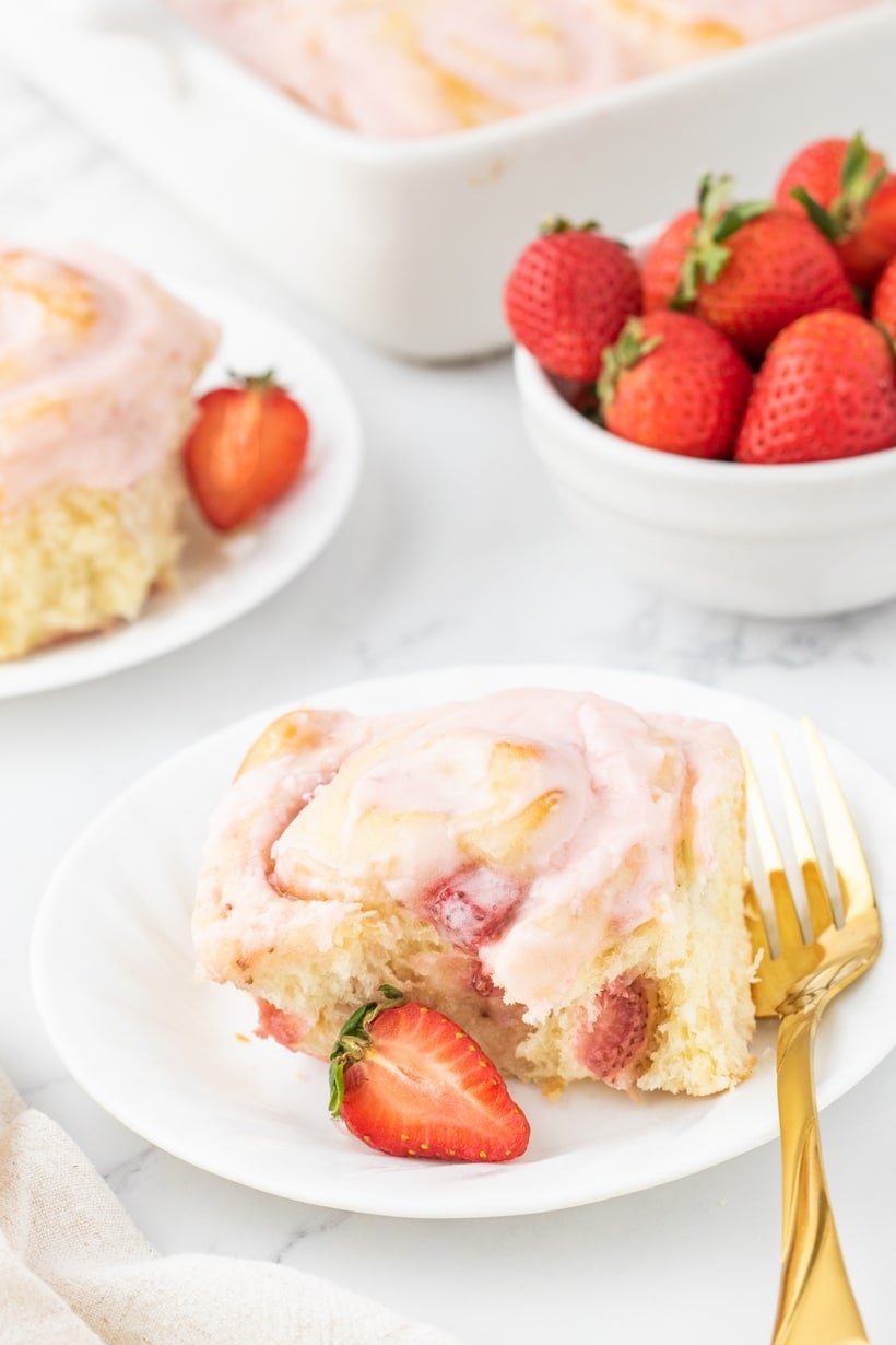 Strawberry Sweet Rolls on a plate A single strawberry sweet roll on a white plate, garnished with fresh strawberries on the side.