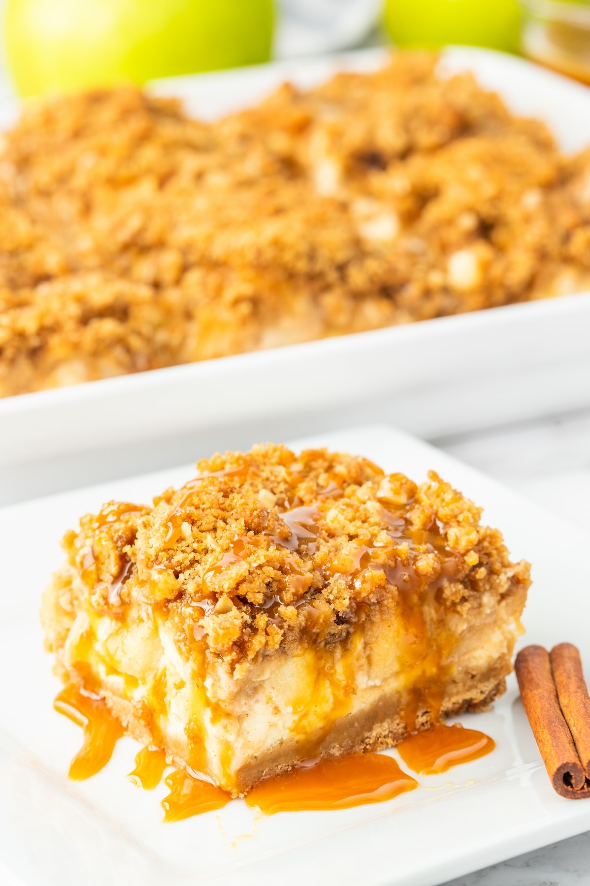 Slice of caramel apple cheesecake bar on a plate with shortbread crust and streusel topping.