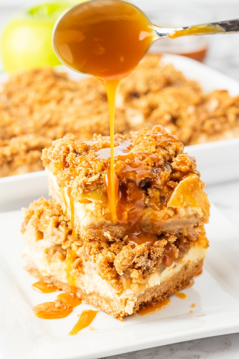 Close-up of apple streusel cheesecake bars with caramel poured over the top.