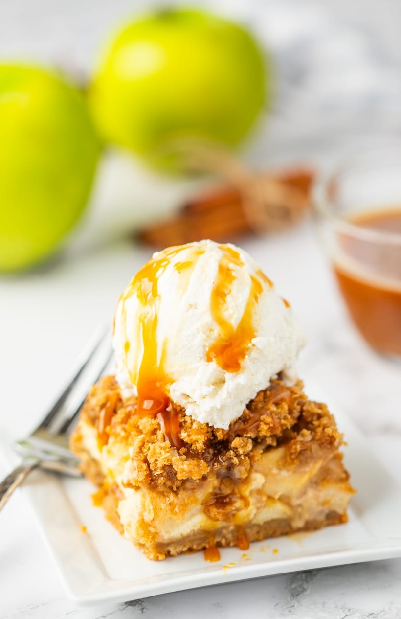 Apple crisp cheesecake bar topped with vanilla ice cream and caramel.