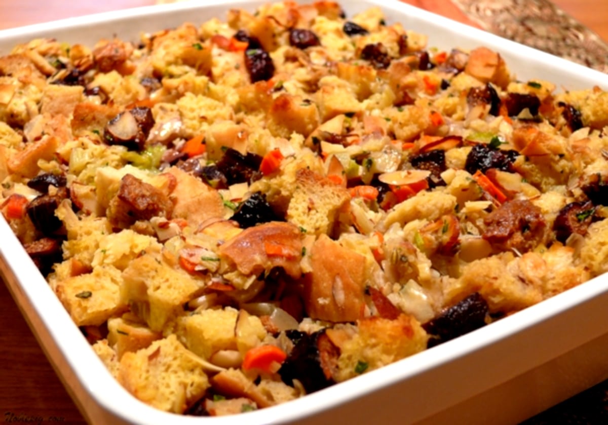 Top view of baked fig and almond stuffing with fennel in white dish Overhead view of fig and almond stuffing with fennel in a white baking dish, showcasing its golden-brown crust and hearty texture.