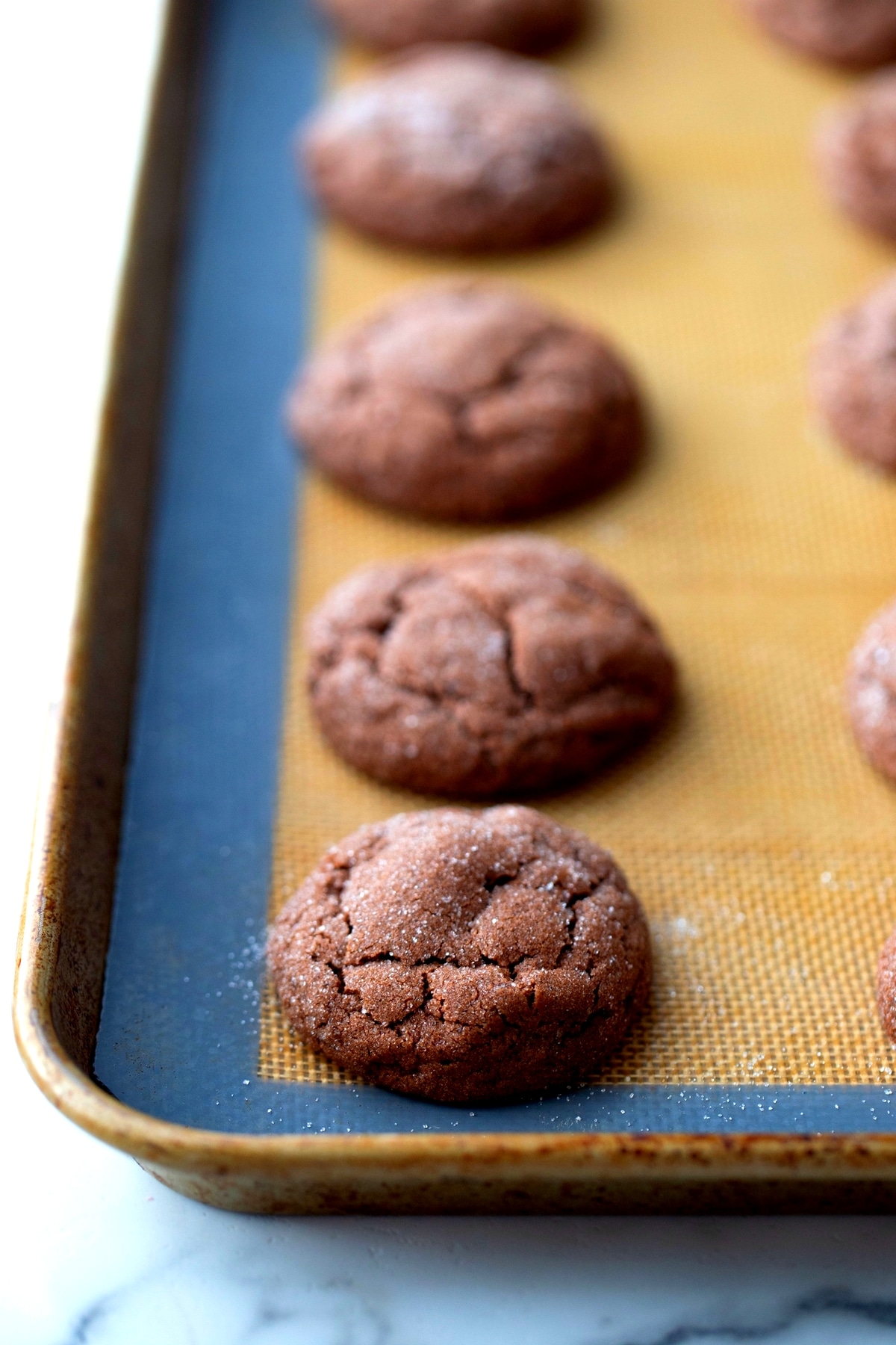 Baked dark chocolate peppermint crackle cookies cooling Freshly baked Dark Chocolate Peppermint Crackle Cookies cooling on a silicone mat.