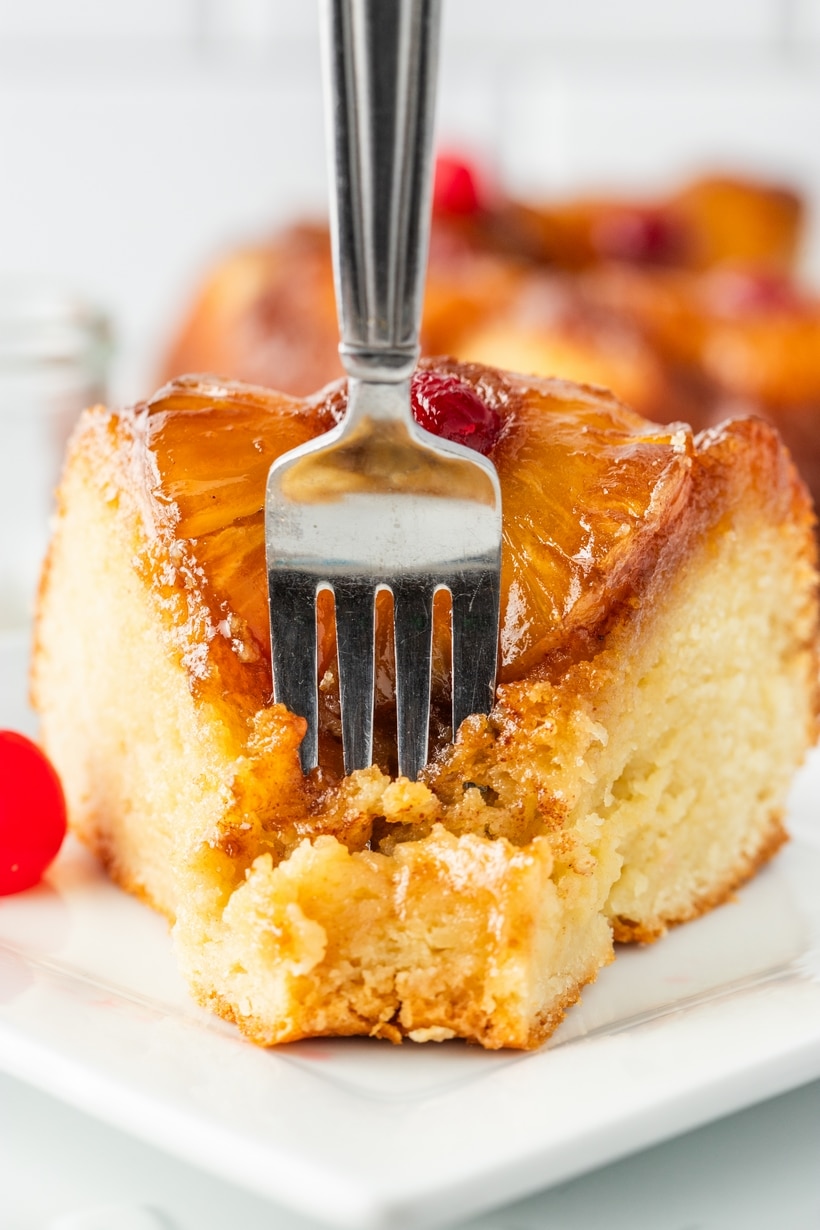 Close-up of a slice of pineapple upside down Bundt cake with a fork pressed into the tender Greek yogurt crumb and caramelized topping.