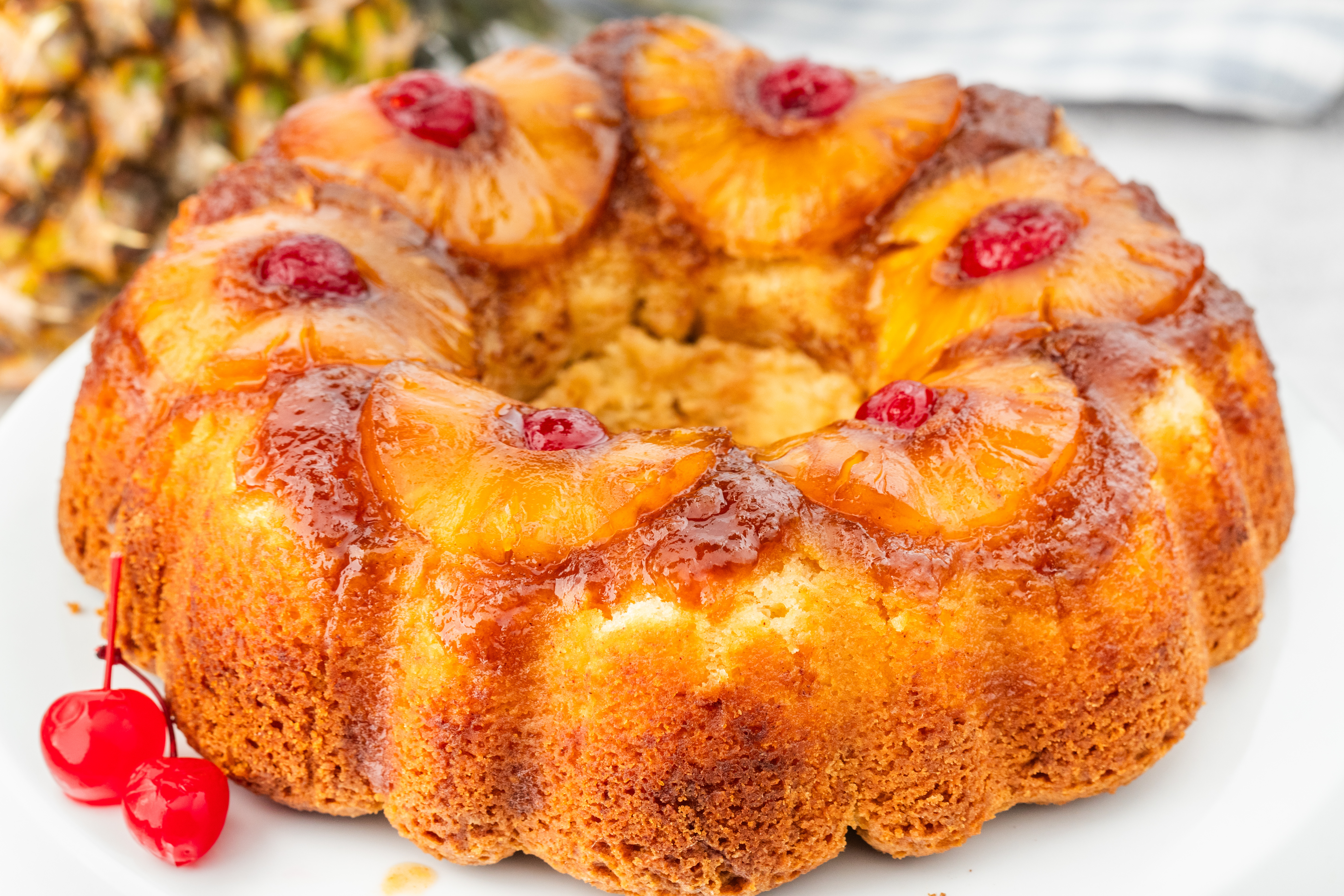Full pineapple upside down Bundt cake with Greek yogurt topped with caramelized pineapple slices and maraschino cherries.