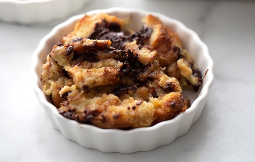 Chocolate Croissant Bread Pudding in a ramekin A serving of chocolate croissant bread pudding in a small ramekin, with a golden, slightly crisp top and gooey chocolate throughout.