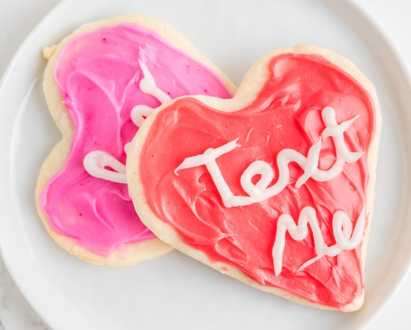 A stack of decorated heart-shaped cookies on a plate, showcasing their soft texture and colorful frosting.