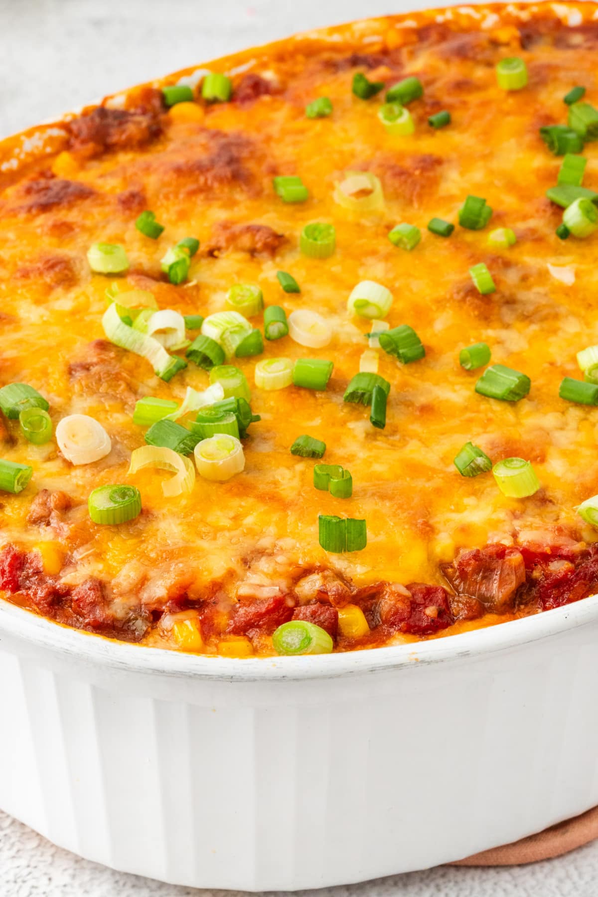 Freshly baked cheesy ground beef casserole with peppers and pasta Baked ground beef casserole with melted cheddar and green onion topping