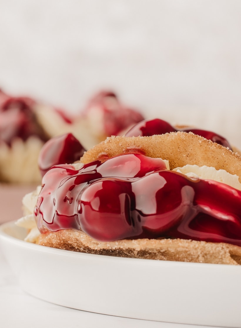 Closeup of Cherry Cheesecake Taco on Its Side Closeup of a single cherry cheesecake taco on its side, showcasing the creamy filling and cherry topping.
