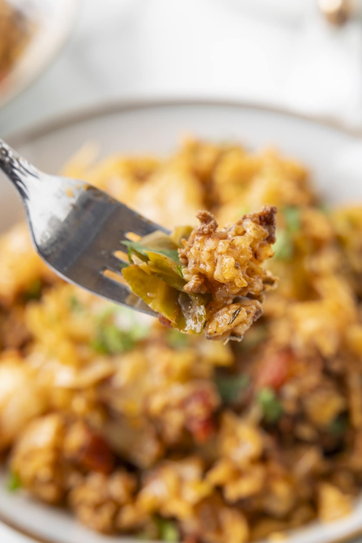 Fork holding a bite of cabbage, beef, and rice from inside out cabbage rolls.