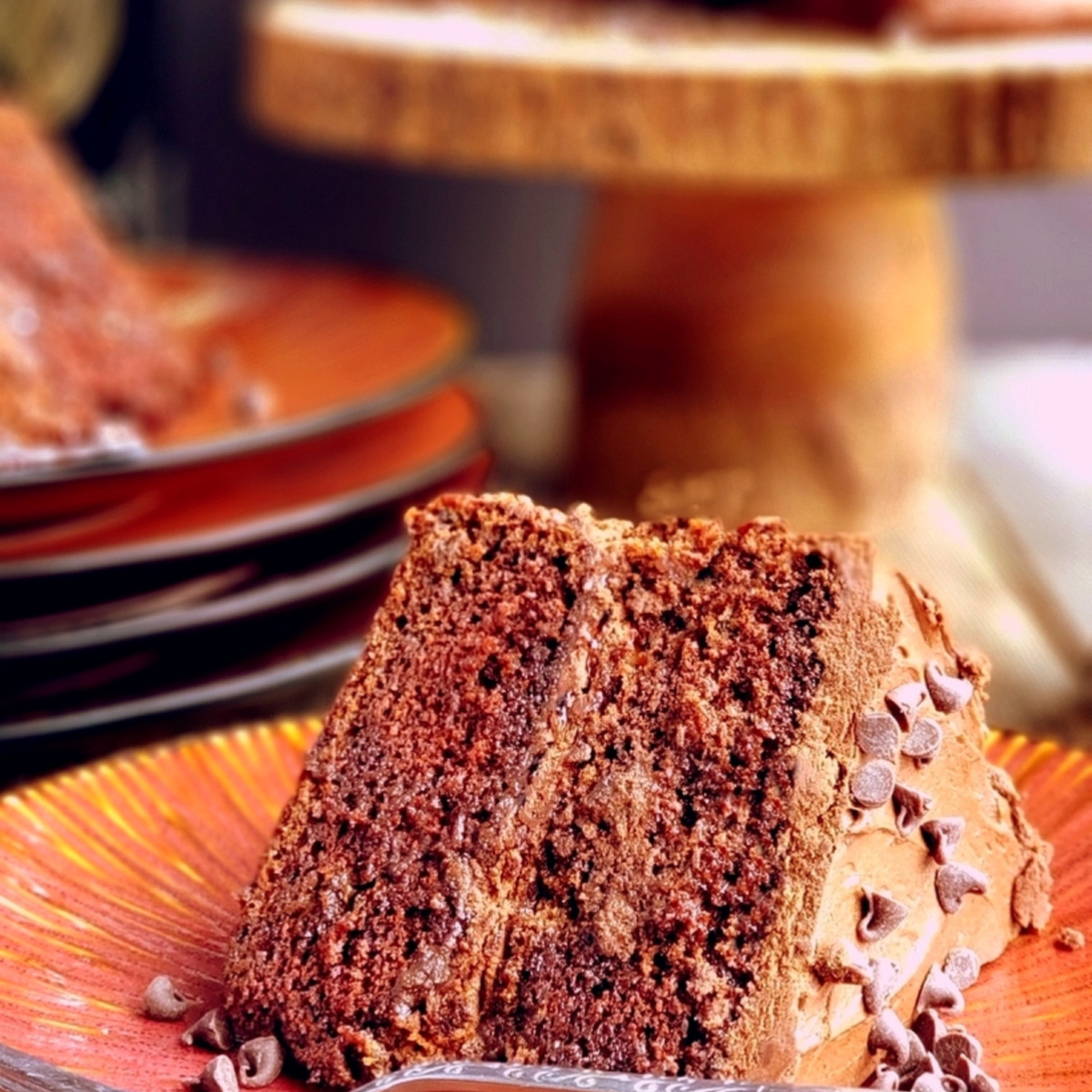 slice of Guinness chocolate layer cake with chocolate icing and mini chocolate chips on an orange plate