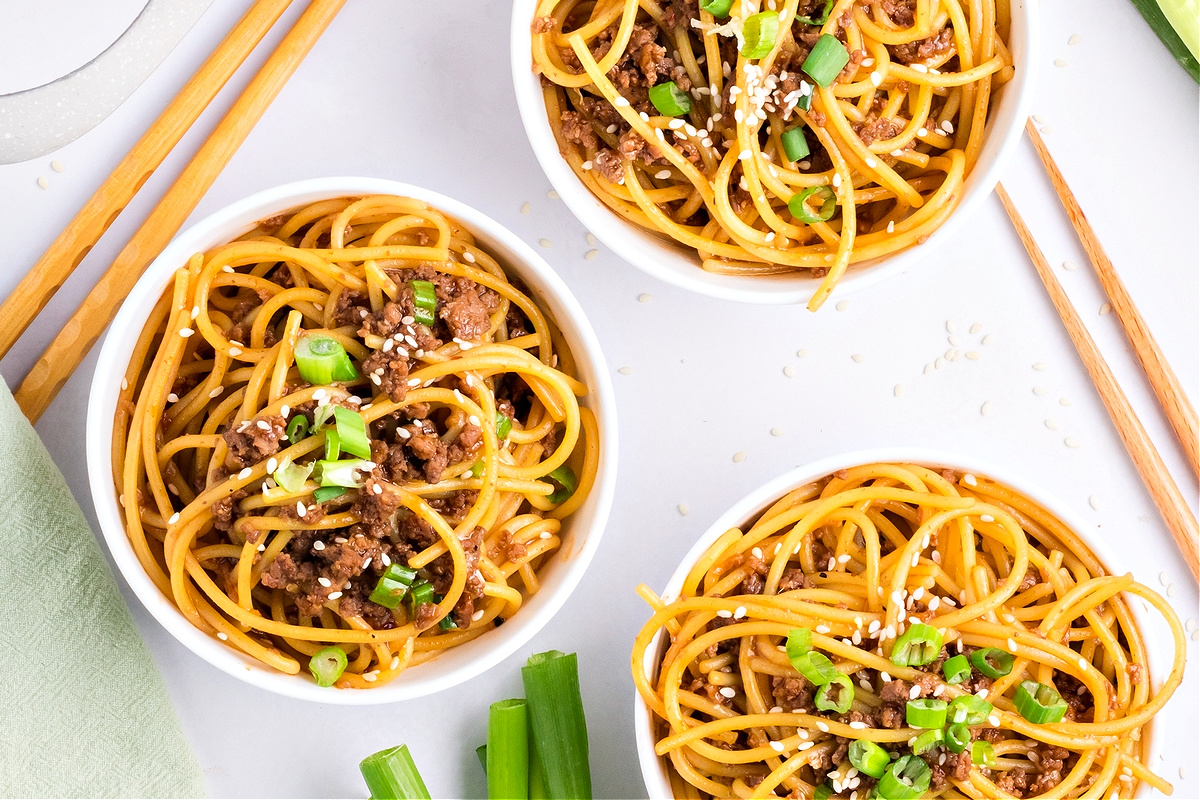 Three bowls of Mongolian beef noodles Three bowls of Mongolian beef noodles garnished with sesame seeds and green onions on a white background by Noble Pig.