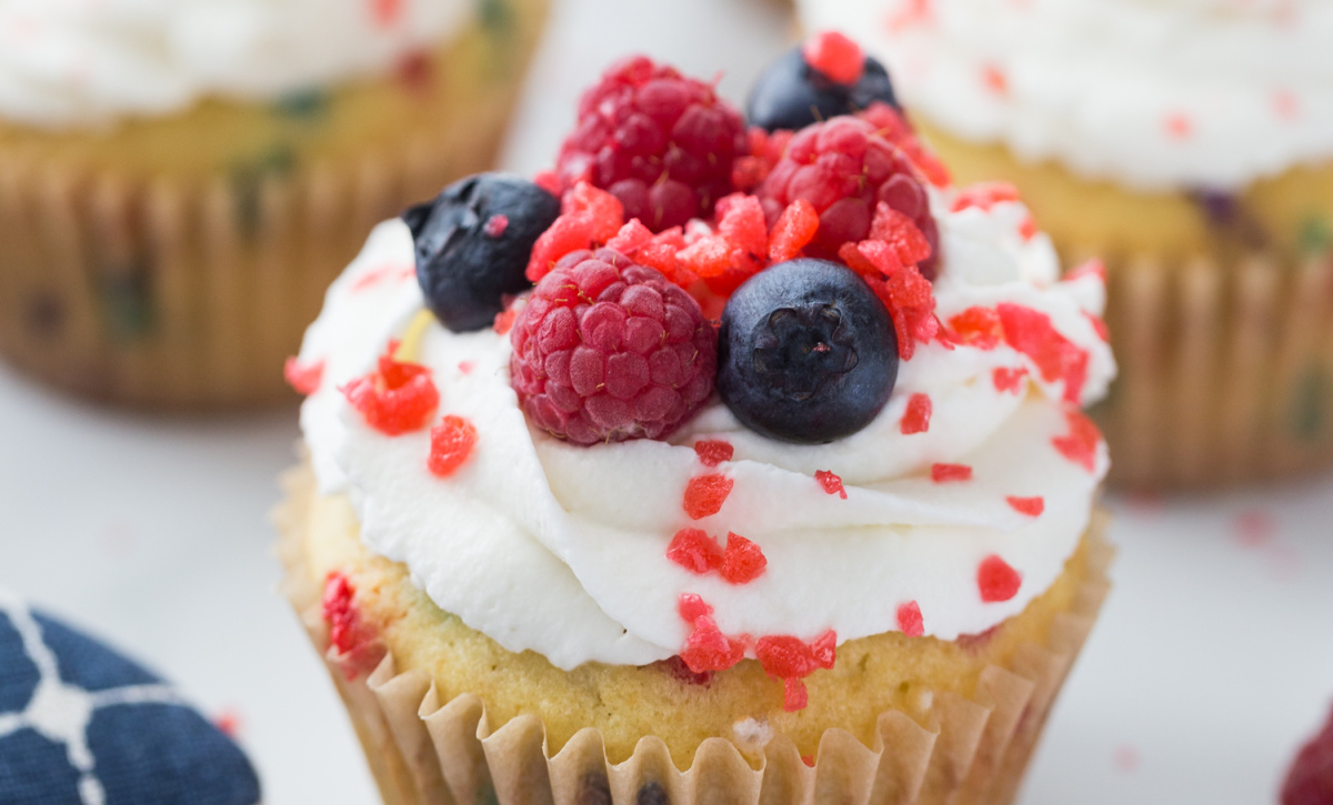 Pop rock cupcakes finished with whipped cream and red, white, and blue. 4th of July cupcakes decorated with whipped cream, berries, and popping candy.