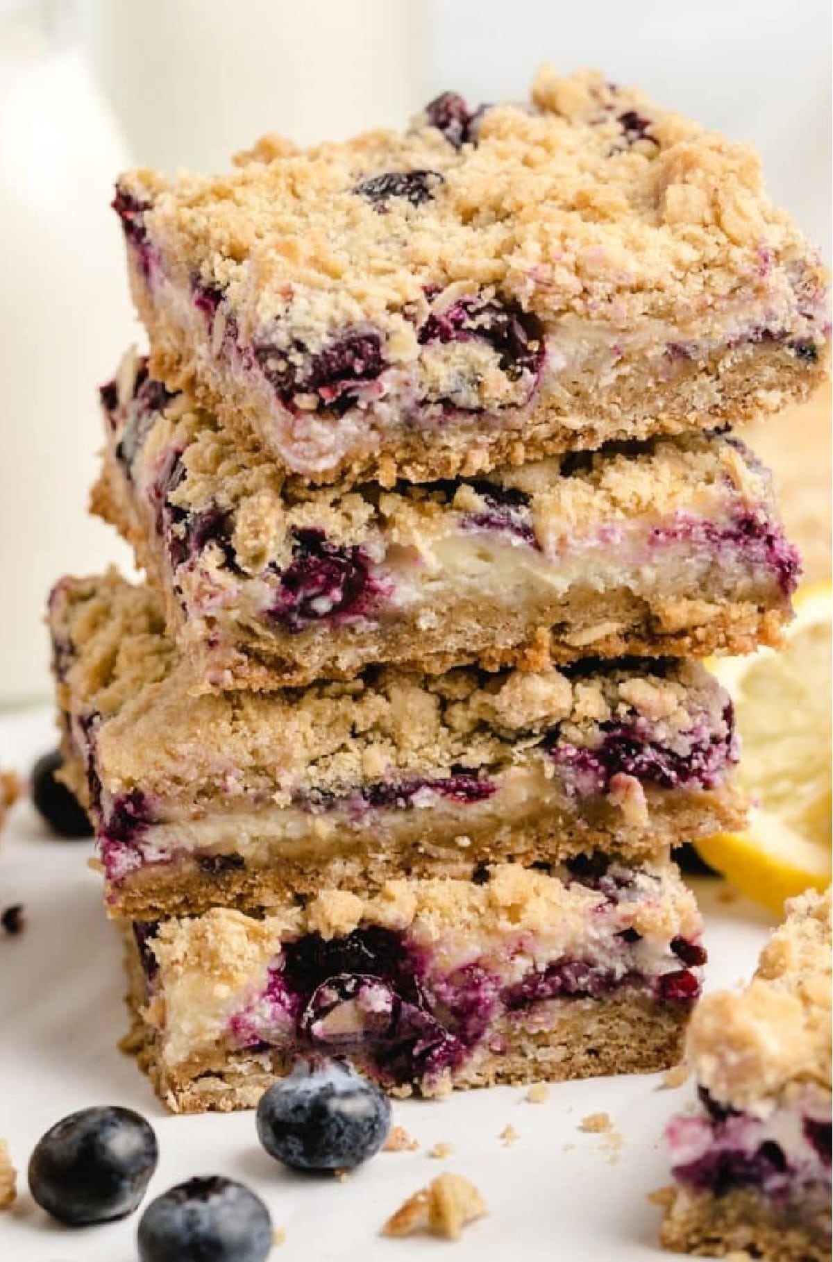 Thick lemon blueberry bars stacked on parchment Stack of lemon blueberry crumble bars showing layers of filling and crumble