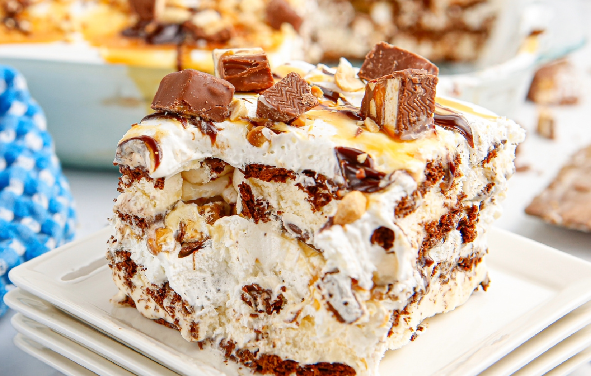 Detailed view of frozen snickers ice cream cake slice with whipped topping and caramel drizzle