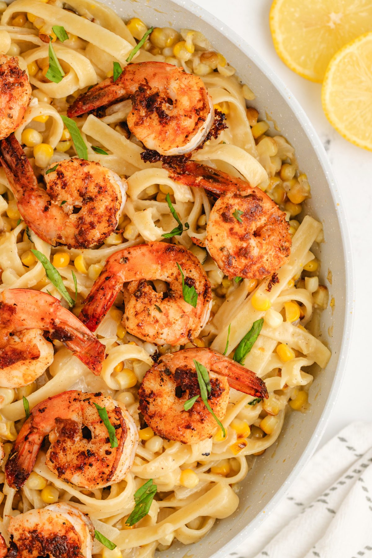 Close-up of blackened shrimp pasta with creamy corn fettuccine in a skillet.