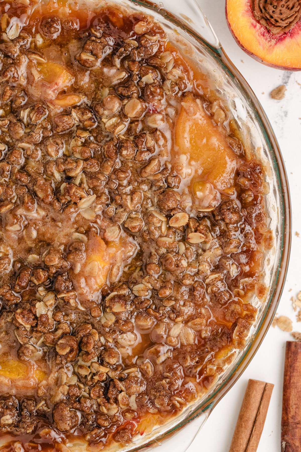 Crisp oat topping over baked peaches. Close-up of golden brown oat topping baked over peaches in a pie dish.