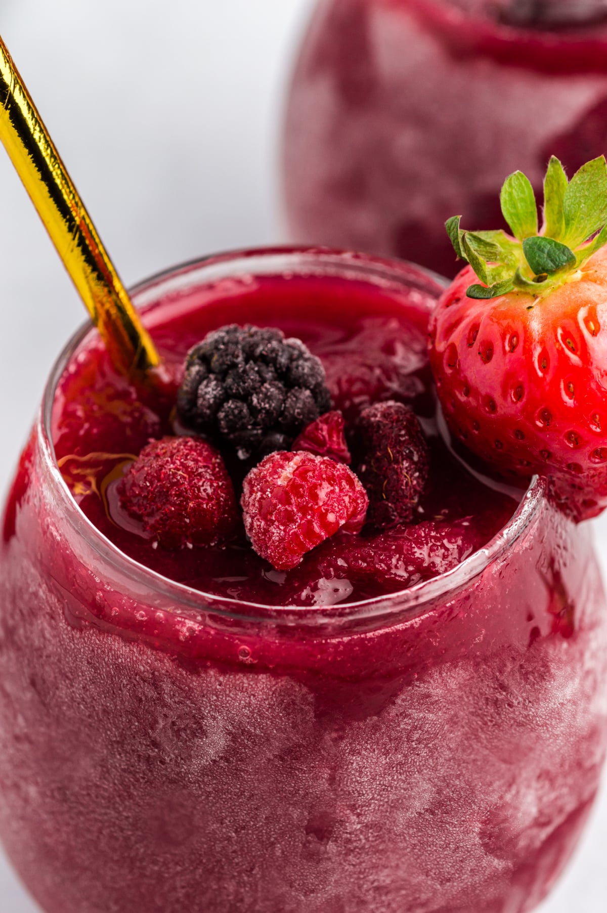 red wine slushie with frozen berries and gold straws Overhead of slushie mixture in container straight from the freezer