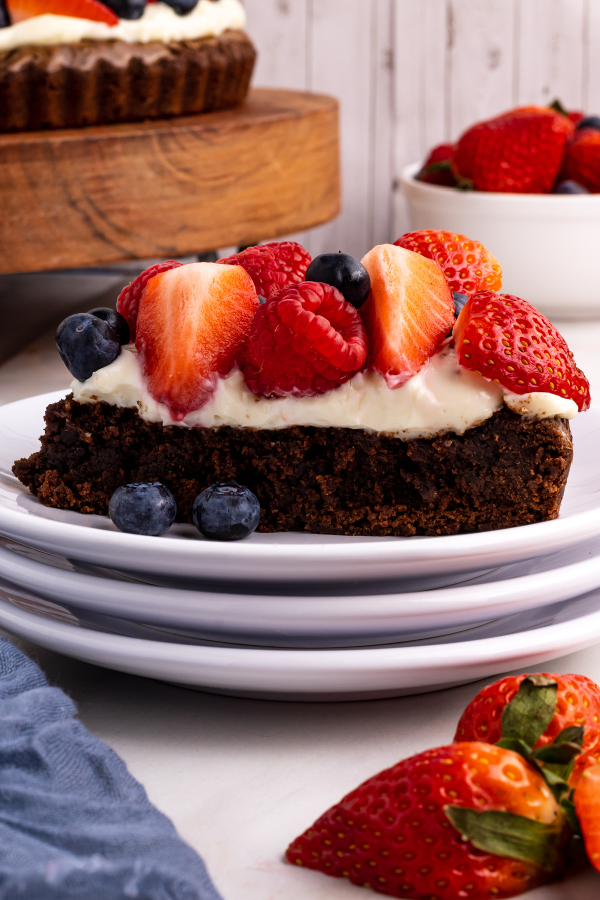 brownie with fruit on top served as a dessert slice Thick slice of brownie fruit pizza on a plate with berries and cream cheese frosting