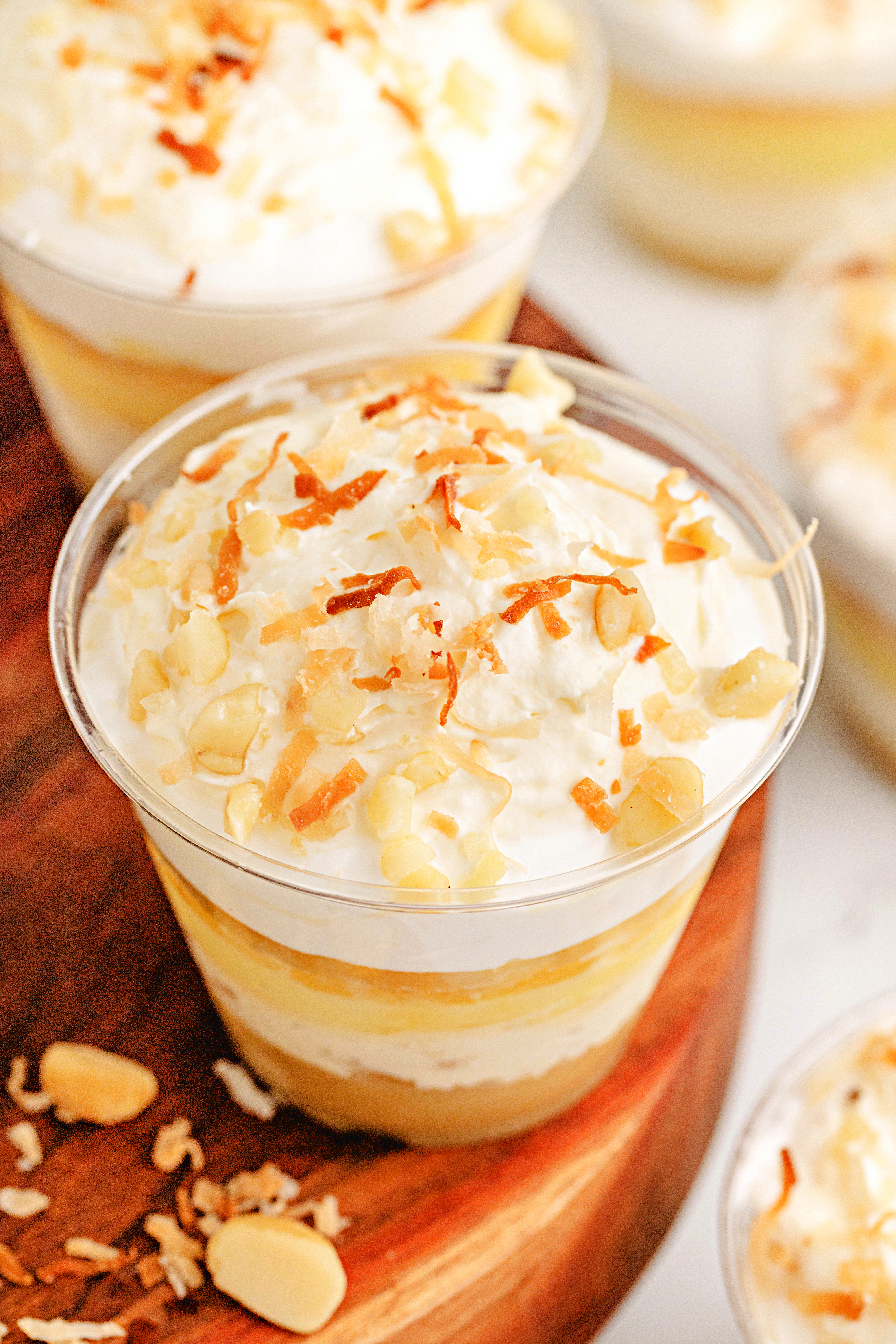 Hawaiian Dream Dessert Cups by Noble Pig with coconut and pineapple layers Close-up of Hawaiian Dream Dessert Cups by Noble Pig with creamy pineapple, coconut, and macadamia layers topped with whipped cream and toasted coconut.