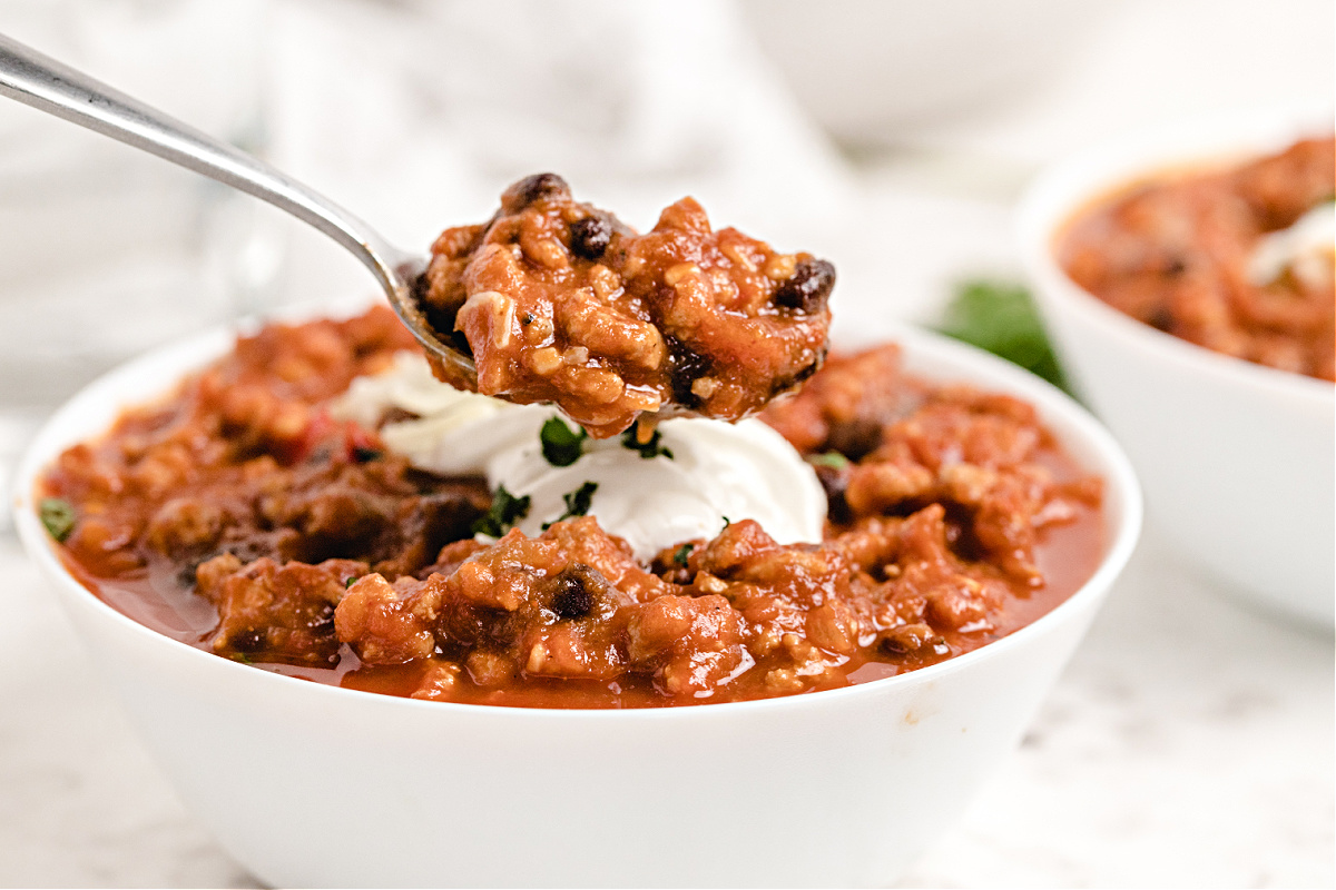 Spoonful of thick pumpkin chili showing beans, turkey, and sauce.