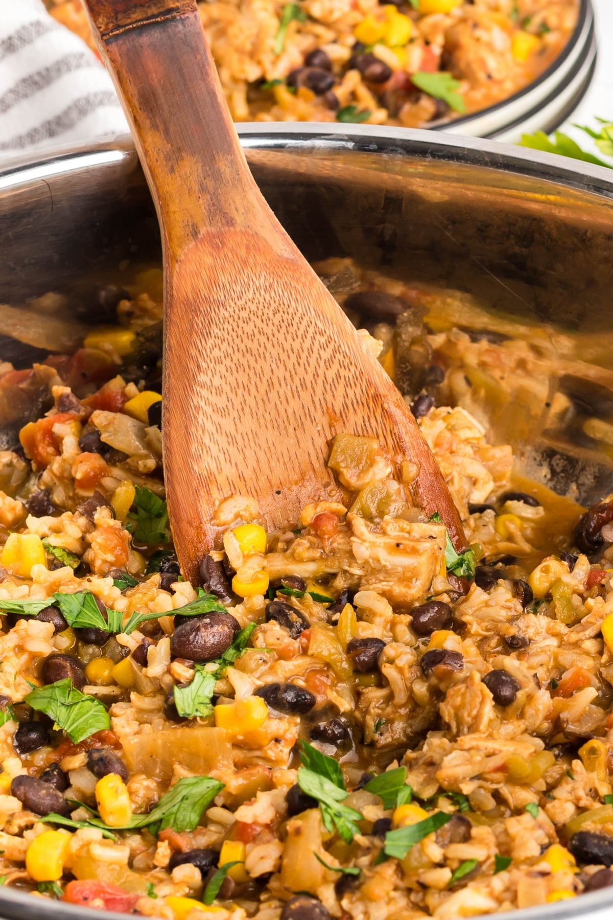 Southwest Turkey Skillet topped with melted cheese and fresh herbs close up of the turkey skillet with a wooden spoon