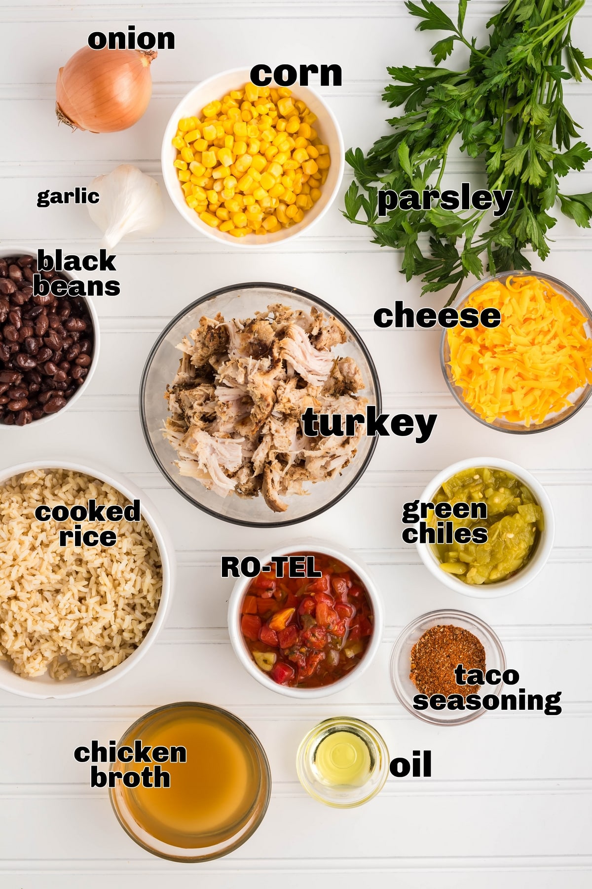 "Ingredients for Southwest Turkey Skillet: diced onions, black beans, corn, tomatoes with green chiles, shredded cheese, vegetable stock, green chiles, taco seasoning, rice, parsley, and cooked turkey pieces Southwest Turkey skillet overhead of all ingredients.