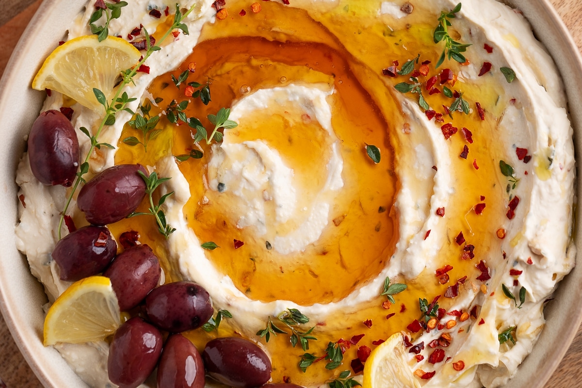 Close-Up of Whipped Feta Roasted Garlic Dip Close-up overhead shot of whipped feta roasted garlic dip with honey, topped with fresh thyme and red pepper flakes.