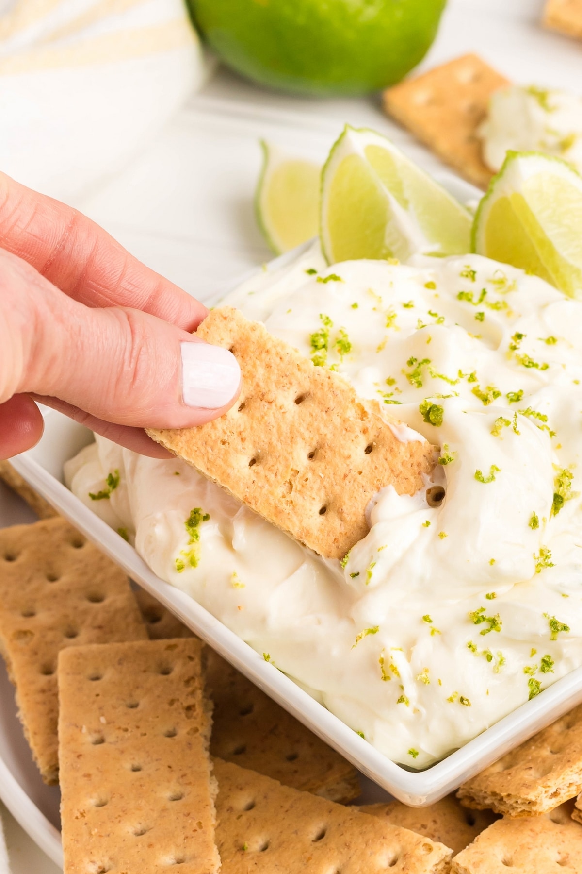 Scooping out a portion of key lime pie dip. A hand scooping out a generous portion of key lime pie dip.
