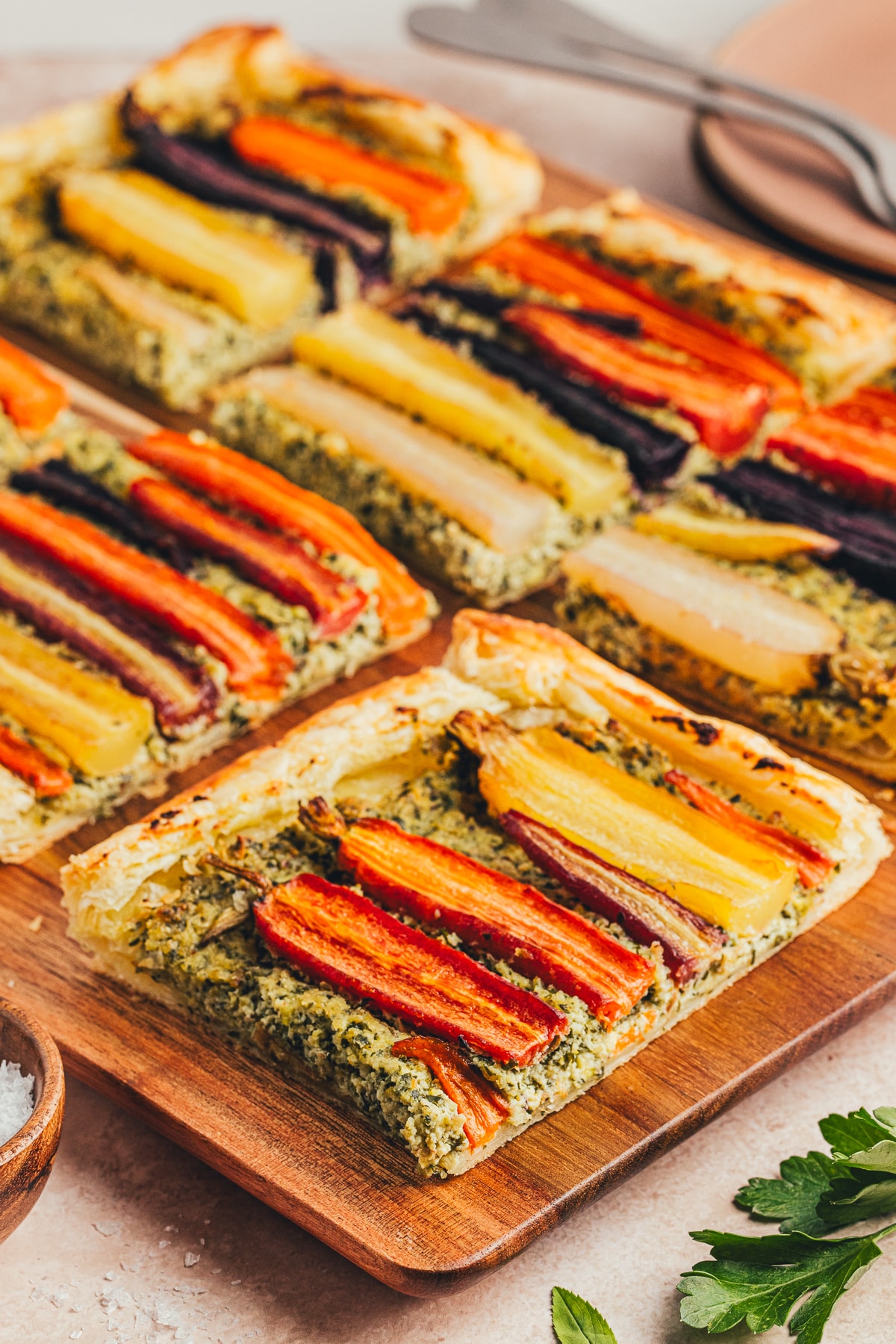 The carrot tart cut into pieces, highlighting the layers of flaky puff pastry, roasted carrots, and creamy pesto-ricotta topping.