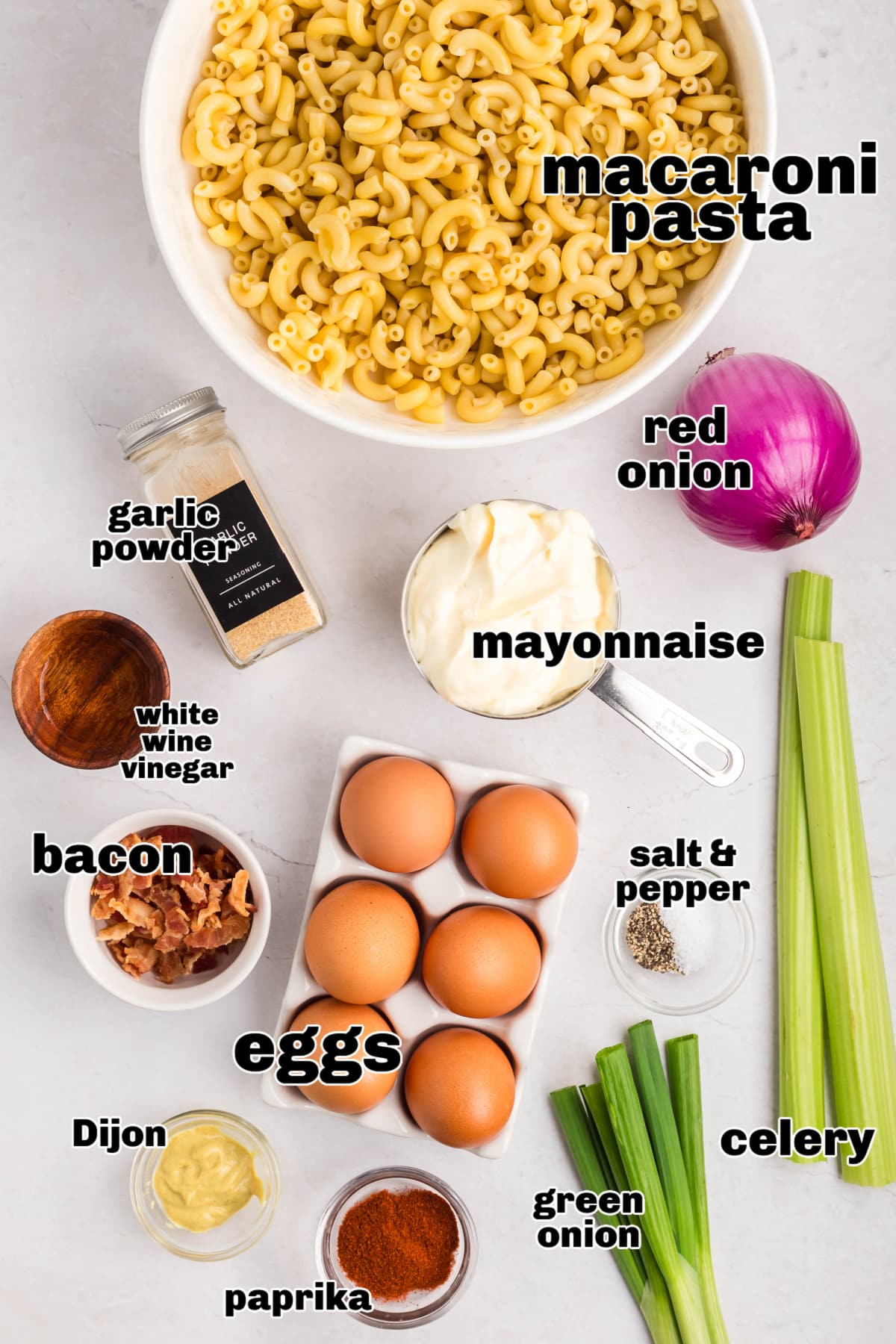 A flat lay of all the ingredients for deviled egg pasta salad, including eggs, pasta, mayo, mustard, bacon, and seasonings.