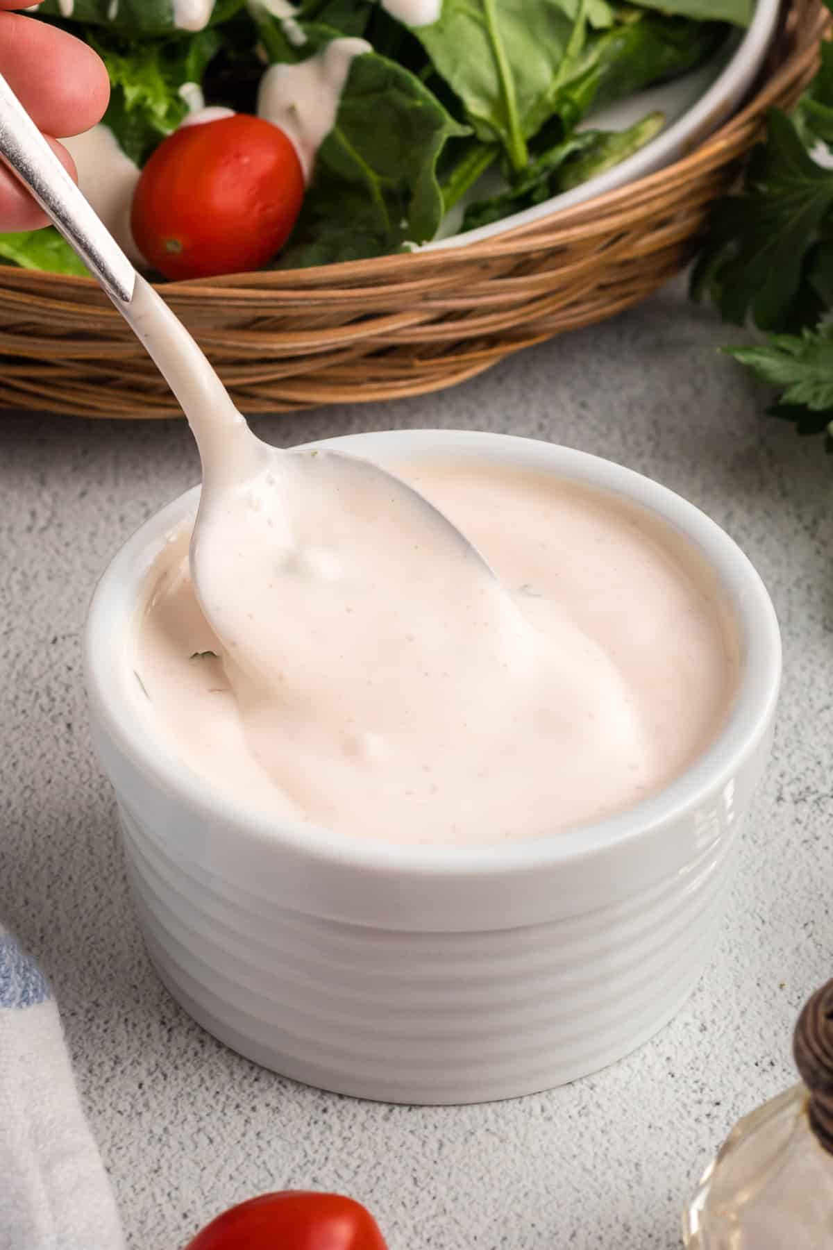 Creamy mayonnaise salad dressing being stirred in a white ramekin with a spoon