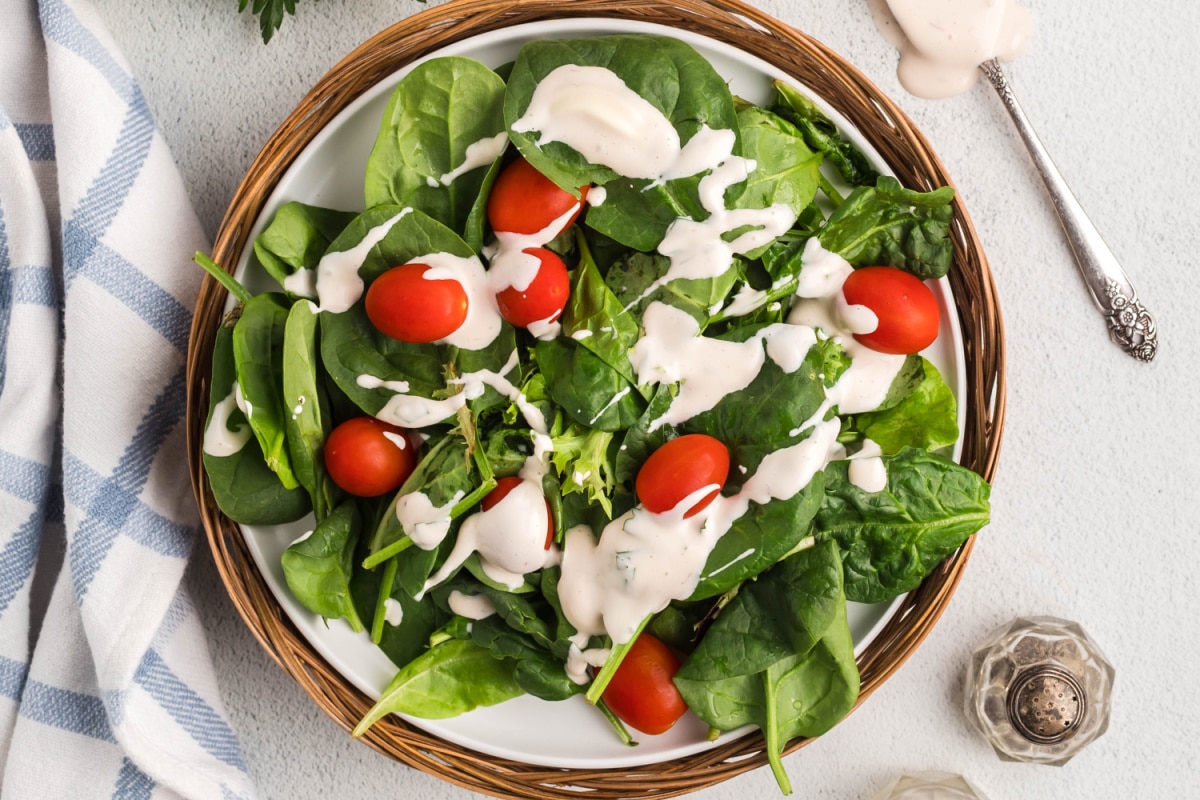 Creamy salad dressing drizzled over fresh spinach leaves