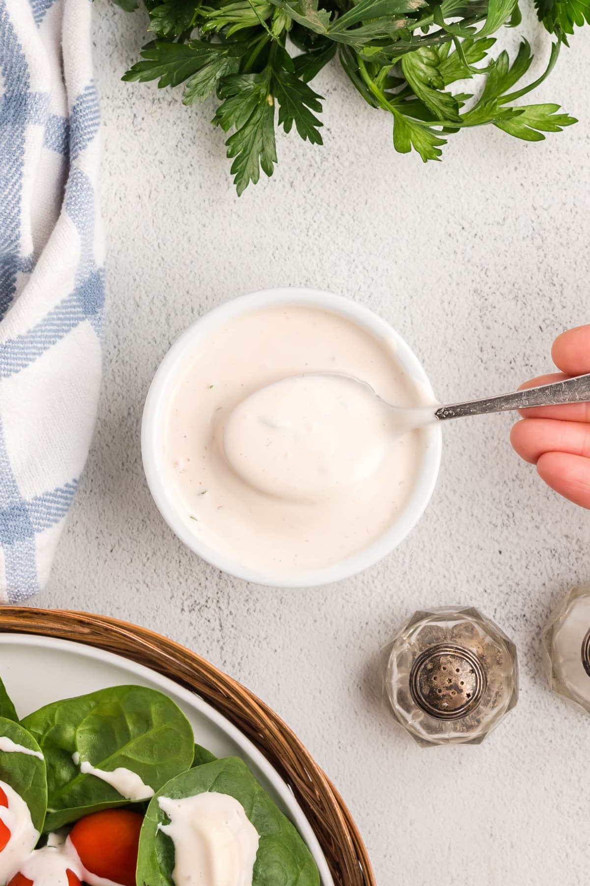 Overhead view of creamy salad dressing in a ramekin with a spoon lifting some out