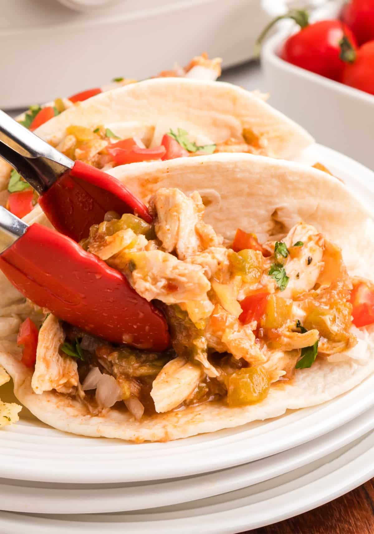 Slow Cooker Shredded Taco Chicken Flat lay of several shredded taco chicken tacos arranged on a platter.